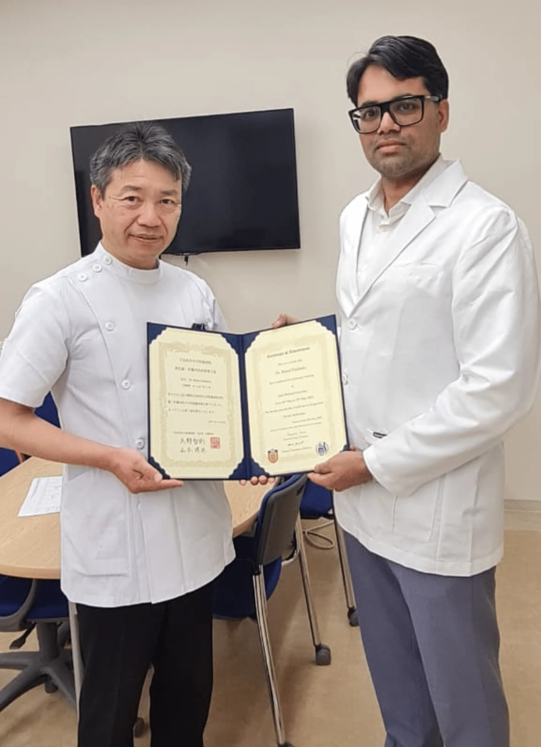 Two healthcare professionals wearing white coats hold a certificate together in a medical office.